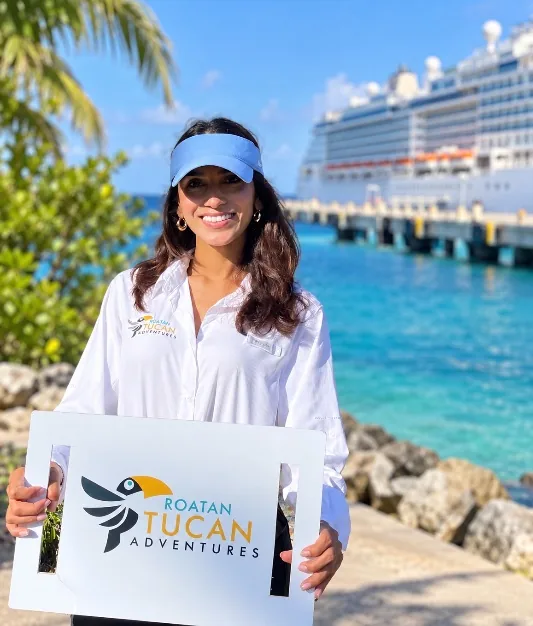 Roatan Tucan Adventures guide holding the company sign next to a cruise ship