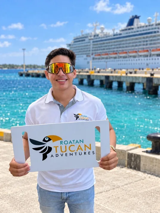 Roatan Tucan Adventures guide holding the company sign at the cruise pier